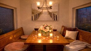 A cozy dining area with a wooden table, two candles, a vase of flowers, and wine glasses. - Bamboo House  (Downtown, Convention Center) 3BR (San Diego)