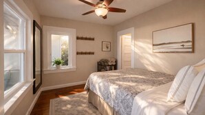 A bedroom with a bed, a ceiling fan, a window, a door, and a framed picture on the wall. - Bamboo House  (Downtown, Convention Center) 3BR (San Diego)