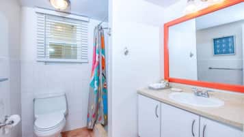 Un baño con inodoro, lavamanos y cortina de ducha.