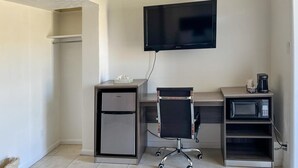 A compact office space with a flat-screen TV mounted on the wall, a refrigerator, a chair, a coffee maker, and a microwave. - Quaint, Lakeside Budget Hotel Room (Everglades City)