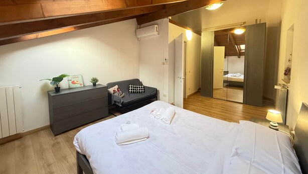 Quarto com cama, mesa de cabeceira, cômoda e espelho.