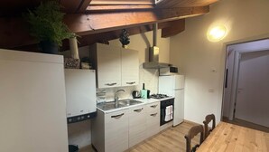 Uma cozinha compacta com claraboia, teto de madeira e área de refeições com mesa e cadeiras de madeira.