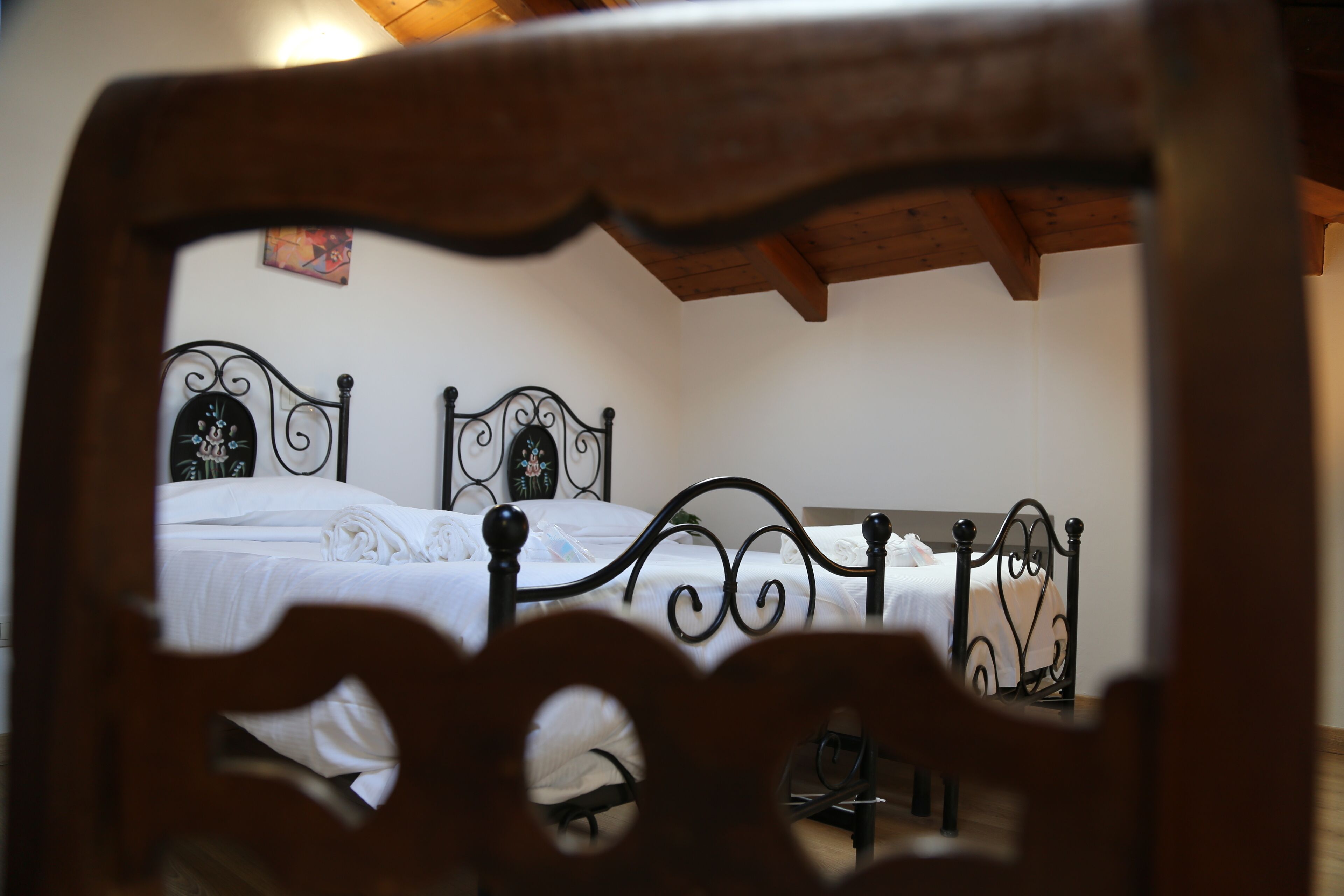 Une chambre à coucher avec un lit, des poutres en bois au plafond et un mur orné d’un tableau.