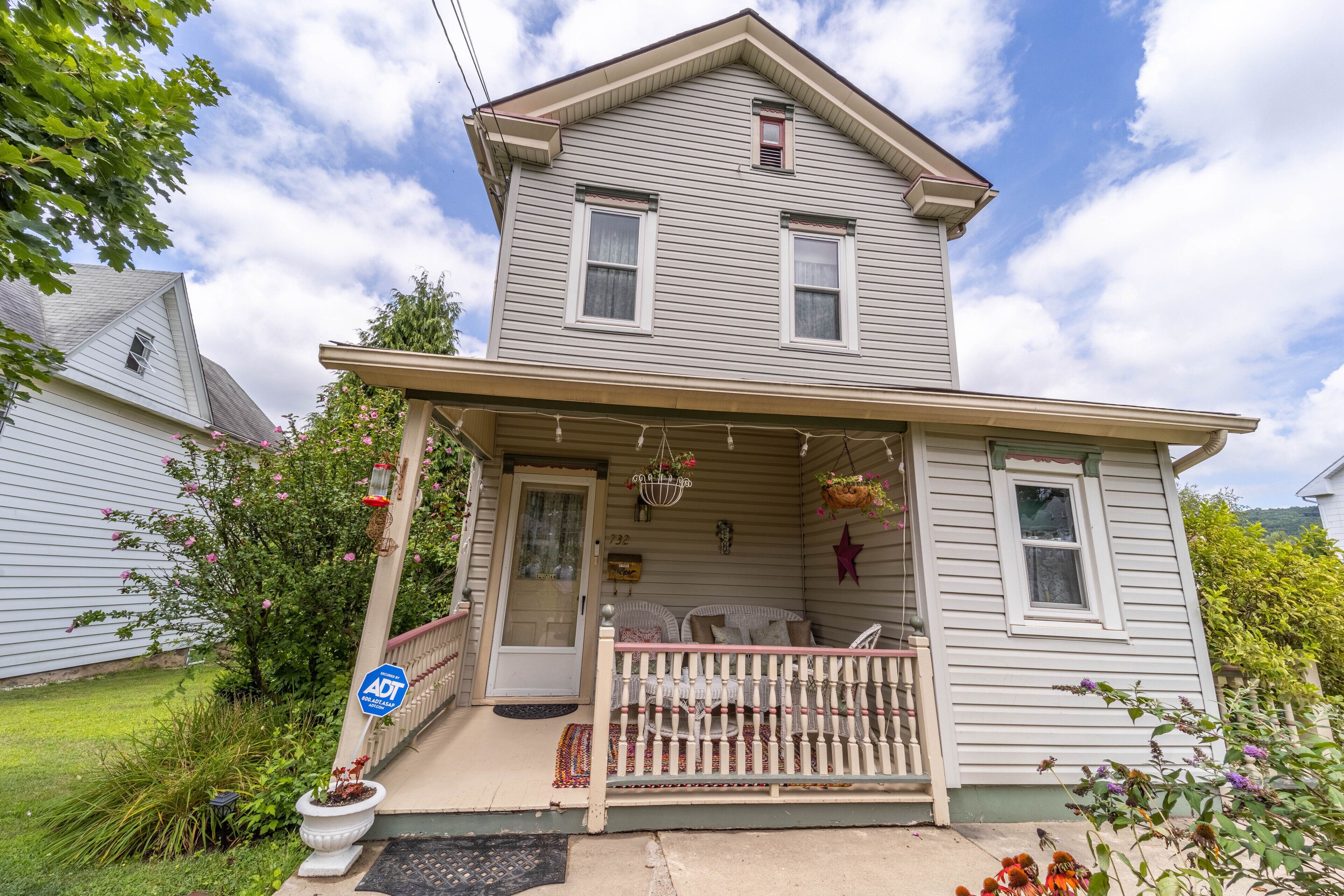 A two-story house with a porch, a front door, and a small window above the door.