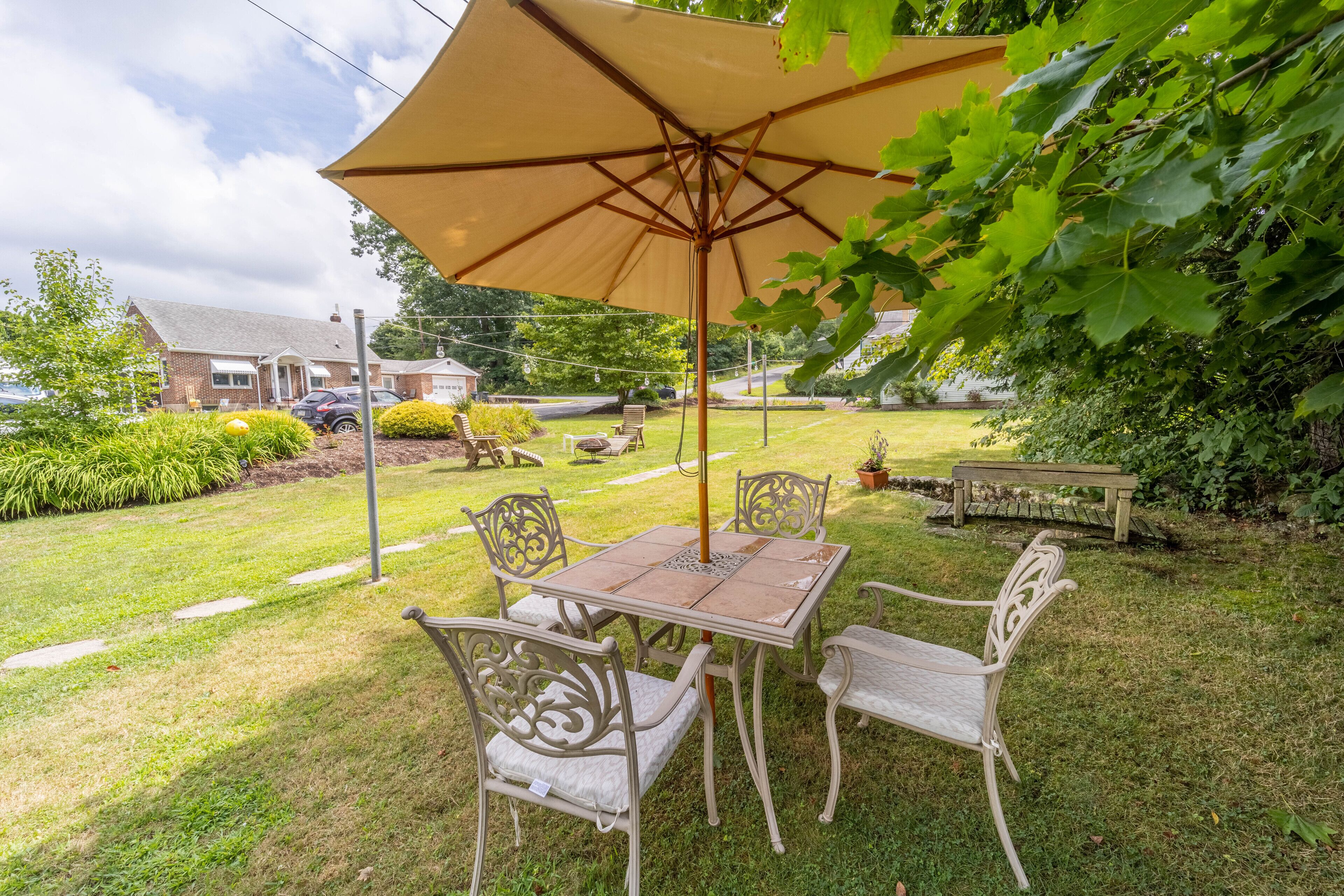 A patio with a table and chairs, an umbrella, and a garden.