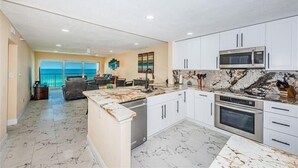 A modern kitchen with white cabinets, a marble countertop, a built-in microwave, and an oven. - Panoramic Gulf Views at Ocean Sands in Madeira Beach~ OS502 (Madeira Beach)