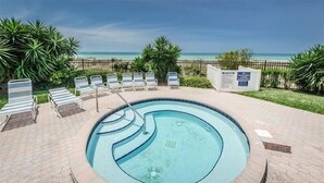 A circular pool with a clear blue center, surrounded by lounge chairs and a view of the beach. - Panoramic Gulf Views at Ocean Sands in Madeira Beach~ OS502 (Madeira Beach)