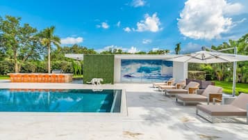Relax by the clear pool surrounded by lush greenery and palm trees.