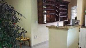 A kitchen with a central island, wooden cabinets, and a potted plant. - Brisas do Farol - Aluguel Economico (Arraial do Cabo)