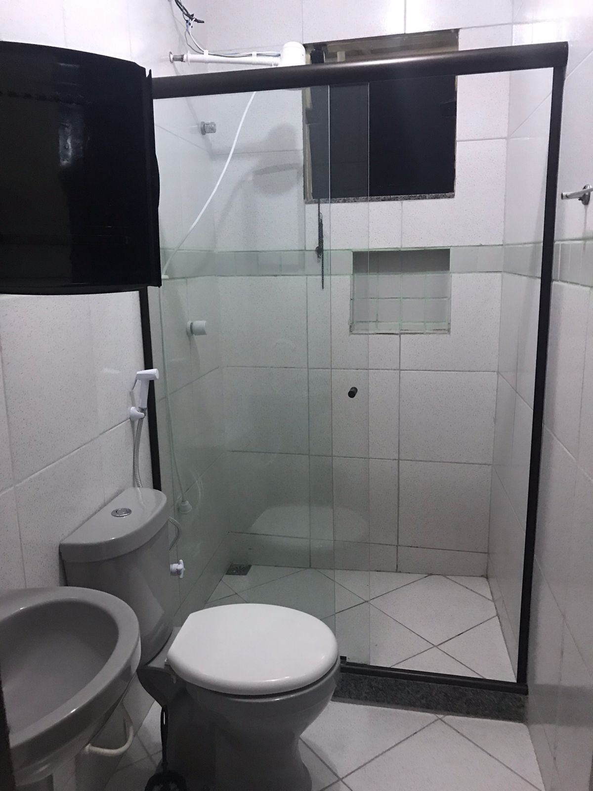 Un baño con inodoro, bidé y cabina de ducha con paredes de vidrio.