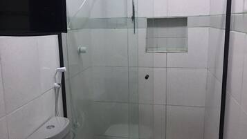 Un baño con inodoro, bidé y cabina de ducha con paredes de vidrio.