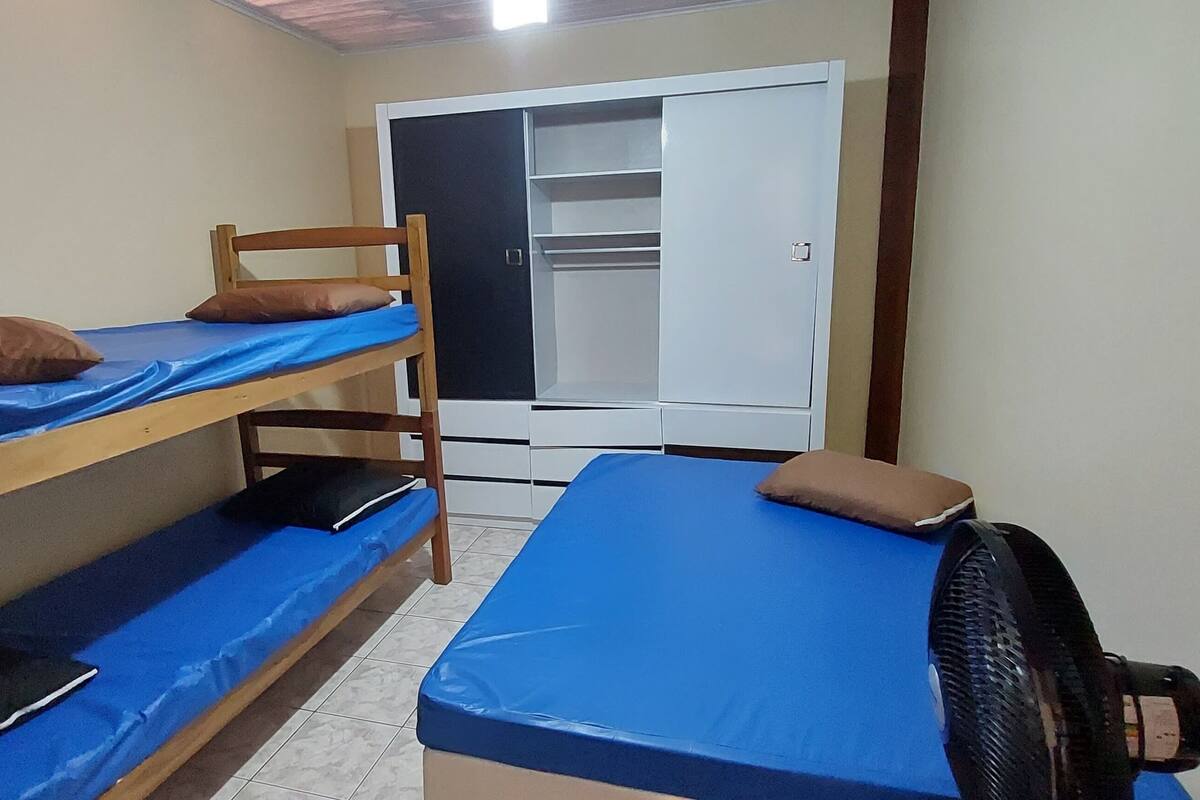 Ein Schlafsaalzimmer mit Etagenbetten, einem Kleiderschrank und einem Ventilator.