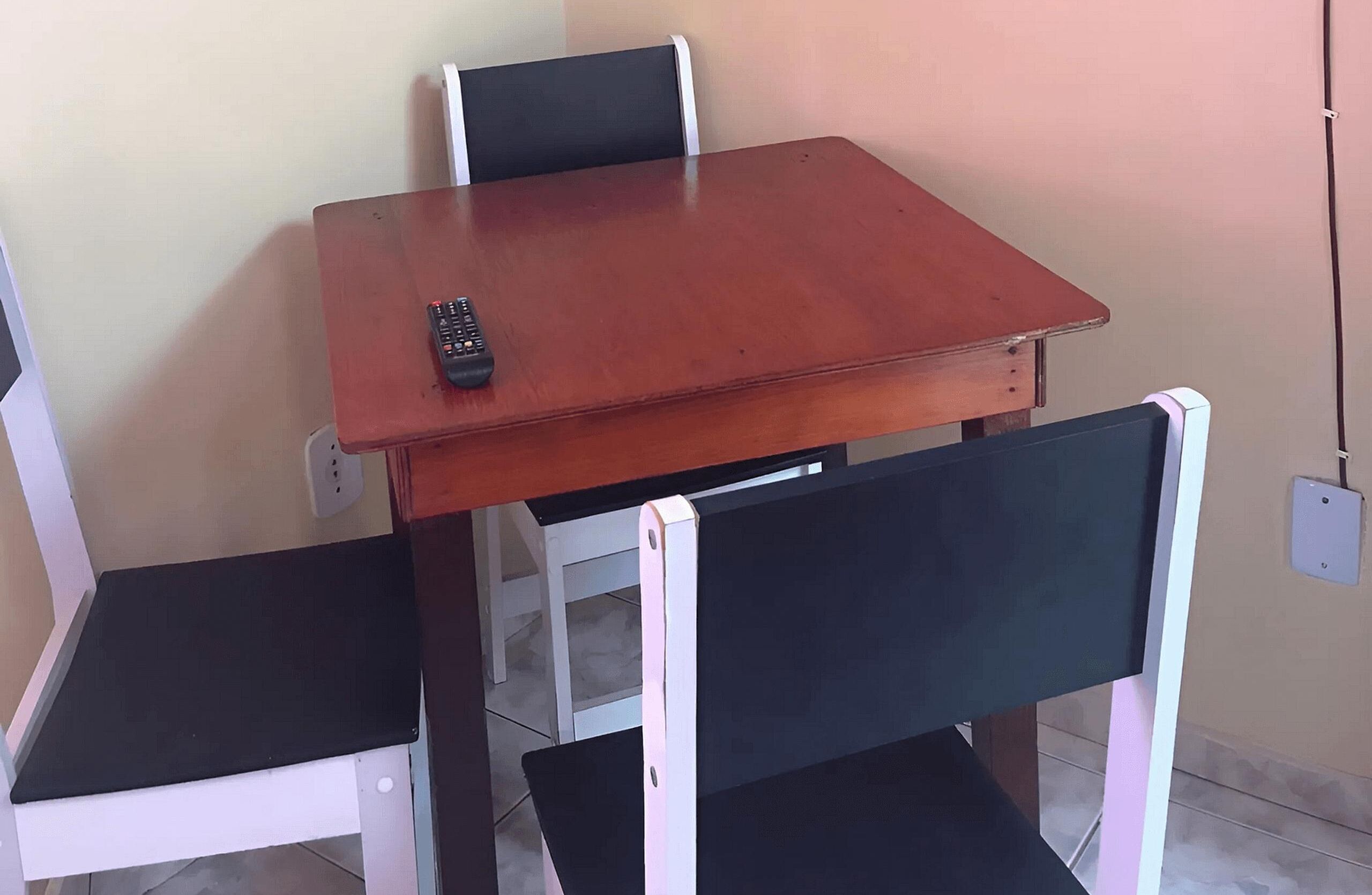 A small dining area with a wooden table and two black chairs.
