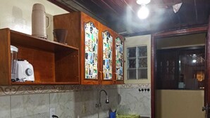 A compact kitchen with a gas stove, a built-in oven, a sink, and wooden cabinets with decorative glass panels. - Brisas do Farol - Aluguel Economico (Arraial do Cabo)
