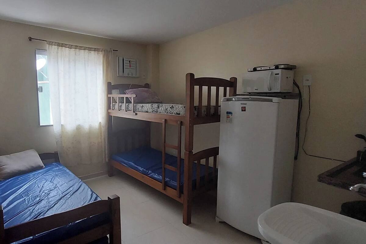 Ein kleiner, kompakter Raum mit einem Etagenbett, einem Schreibtisch mit Stuhl, einem Kühlschrank und einem kleinen Waschbecken.
