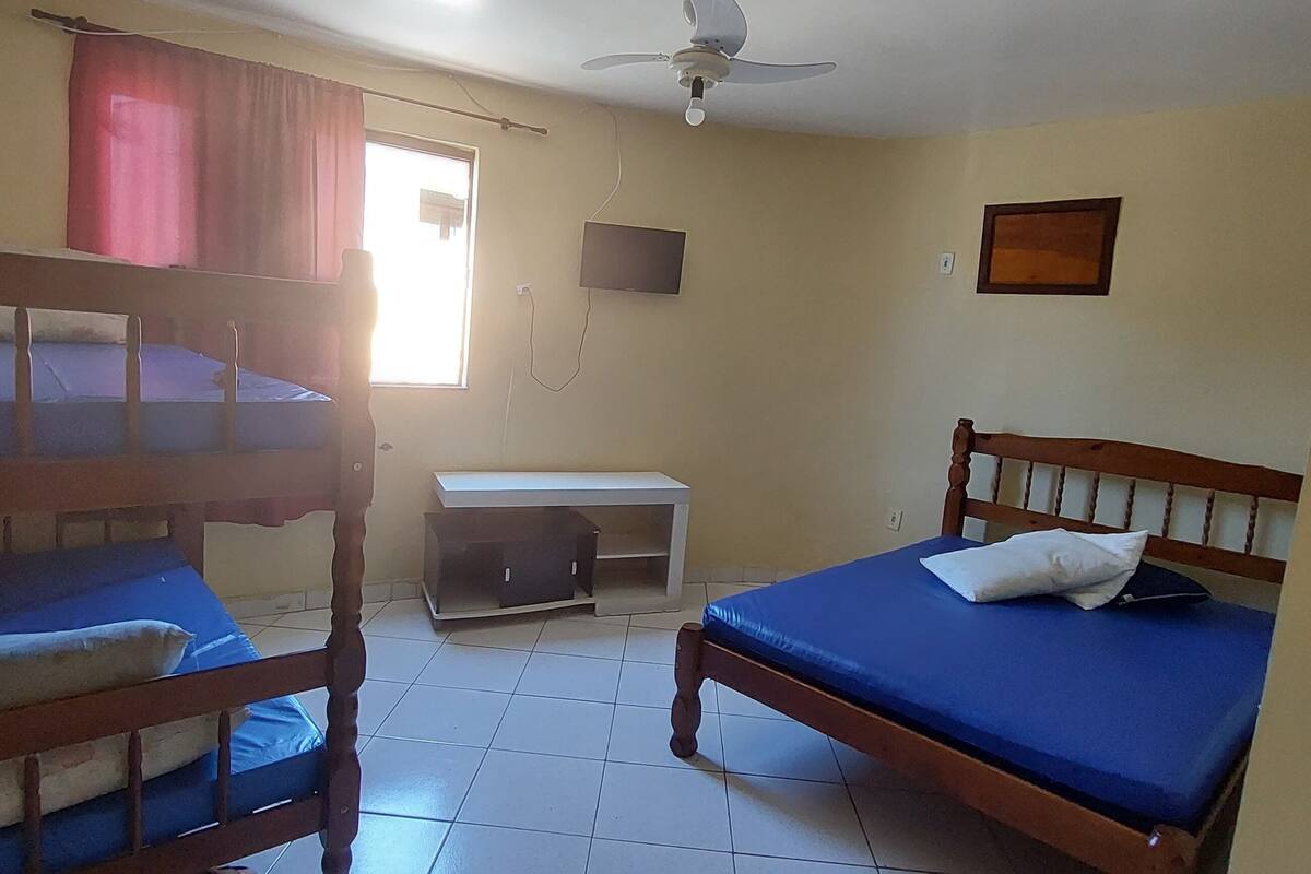 Ein Schlafsaalzimmer mit Etagenbetten, einem Schreibtisch, einem Stuhl und einem Deckenventilator.