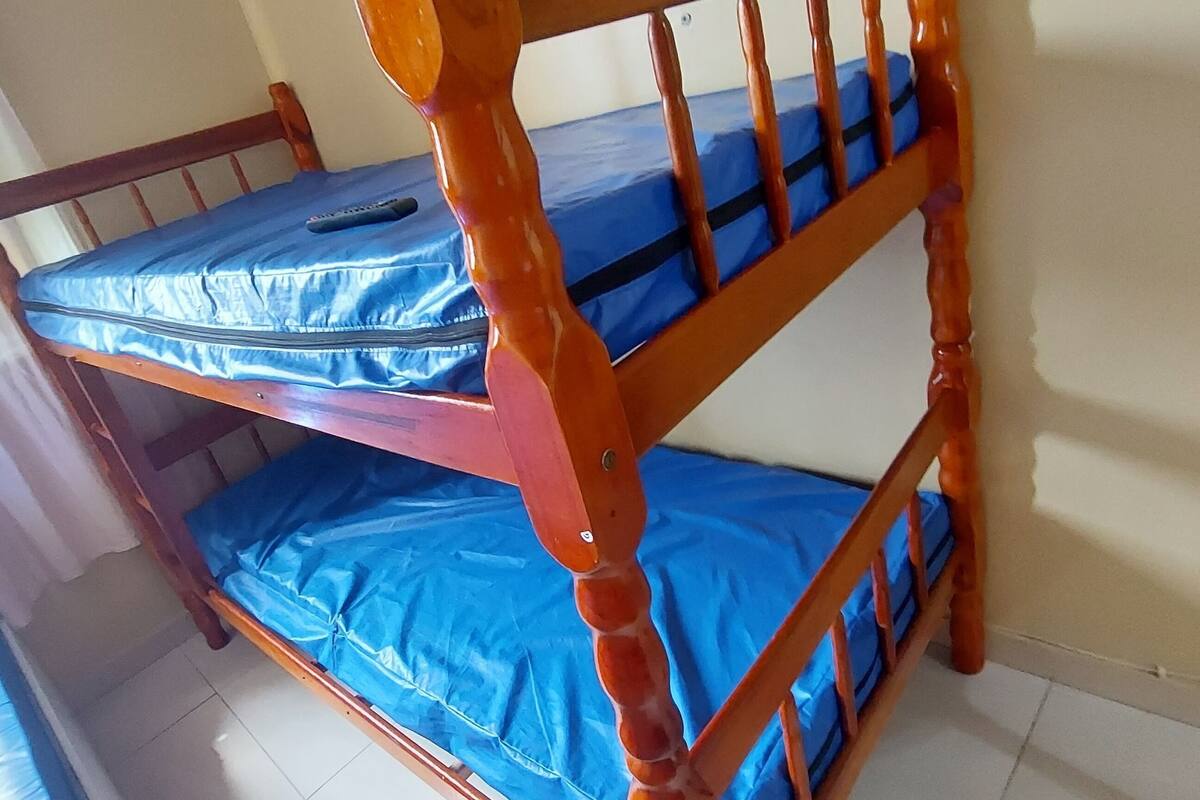 Ein Etagenbett mit blauer Bettwäsche und einer Fernbedienung auf dem oberen Bett.