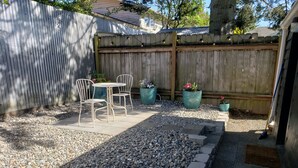 A patio area with a table and chairs, surrounded by pebbles and potted plants.