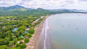 A coastal area with a beach, boats, and lush greenery. - Sunset 303 - Ocean View 3 BR Condo (Potrero)