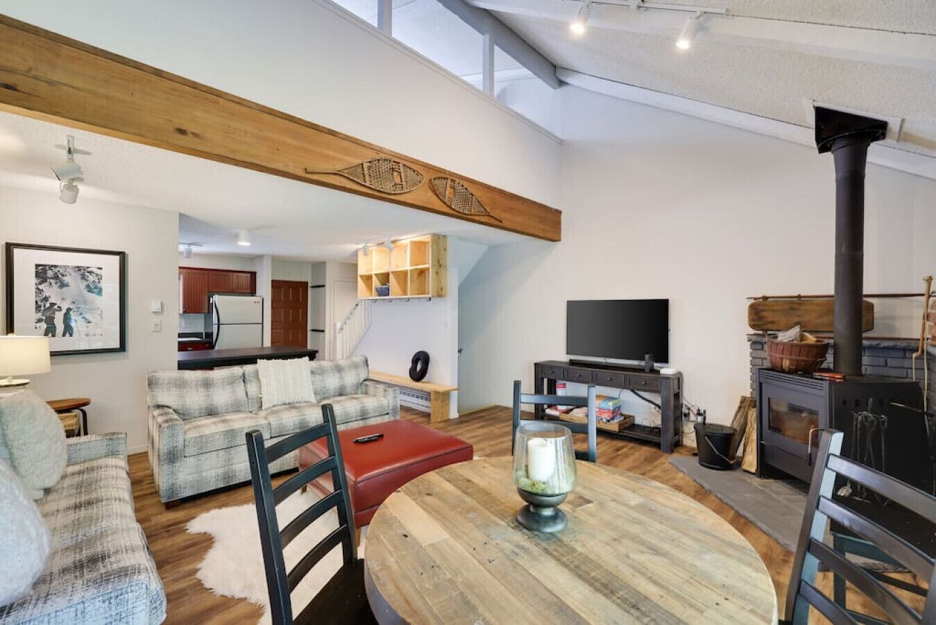 A cozy living room with a wooden ceiling, a fireplace, a dining table, and a TV.
