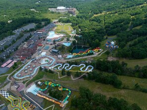 An aerial view of a theme park with various attractions, including a winding water slide, a large pool, and a racetrack.