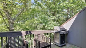 A wooden deck with a grill and two chairs, surrounded by trees. - Spectacular Pocono's Getaway Near EVERYTHING!!! (Tannersville)