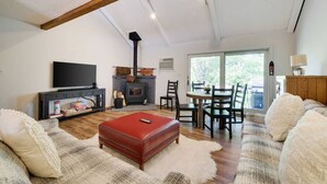 A living room with a fireplace, a television, and a dining area with chairs and a table. - Spectacular Pocono's Getaway Near EVERYTHING!!! (Tannersville)