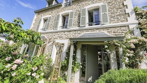 A stone building with a balcony, a wooden ladder, and a door.