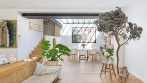 A modern living space with a staircase, a dining area, and a large plant.