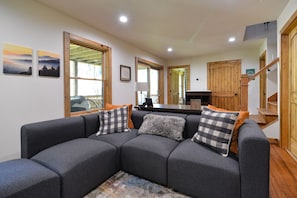 Relax in this stylish living room with a comfortable sofa, framed artwork, and a beautiful staircase.