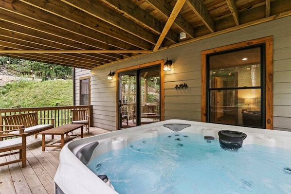 Unwind in a serene outdoor hot tub area with a hot tub, benches, and a table.