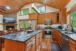Enjoy cooking in this well-equipped kitchen with a large island, microwave, oven, and sink, surrounded by natural views.
