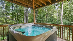 Un jacuzzi en una terraza de madera rodeado de árboles.