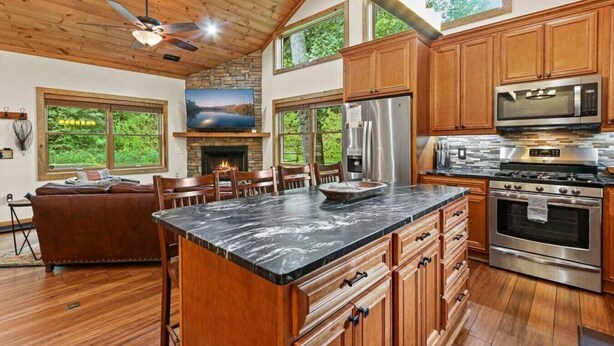 Una cocina amplia con armarios de madera, una isla grande, electrodomésticos de acero inoxidable y una chimenea de piedra.