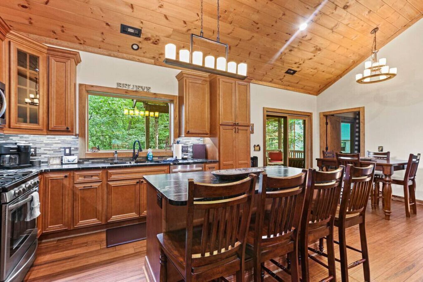 A spacious kitchen with wooden cabinets, a large island, and a dining area with wooden chairs.
