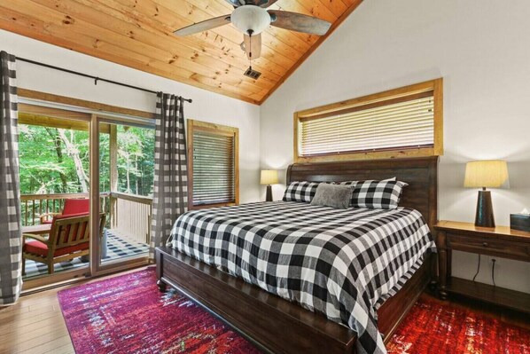 A bedroom with a large bed, a wooden ceiling fan, a balcony with a chair, and a red carpet. - Welcome to Padre`s Mountain Paradise! (Blowing Rock)