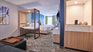 Een hotelkamer met een bed, een bureau, een stoel, een serveerblad en een televisie.