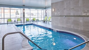 An indoor swimming pool with clear water, a diving board, and lounge chairs. - SpringHill Suites by Marriott Detroit Dearborn (Dearborn)