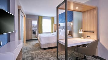 A hotel room with a bed, desk, chair, TV, and a large window with curtains.