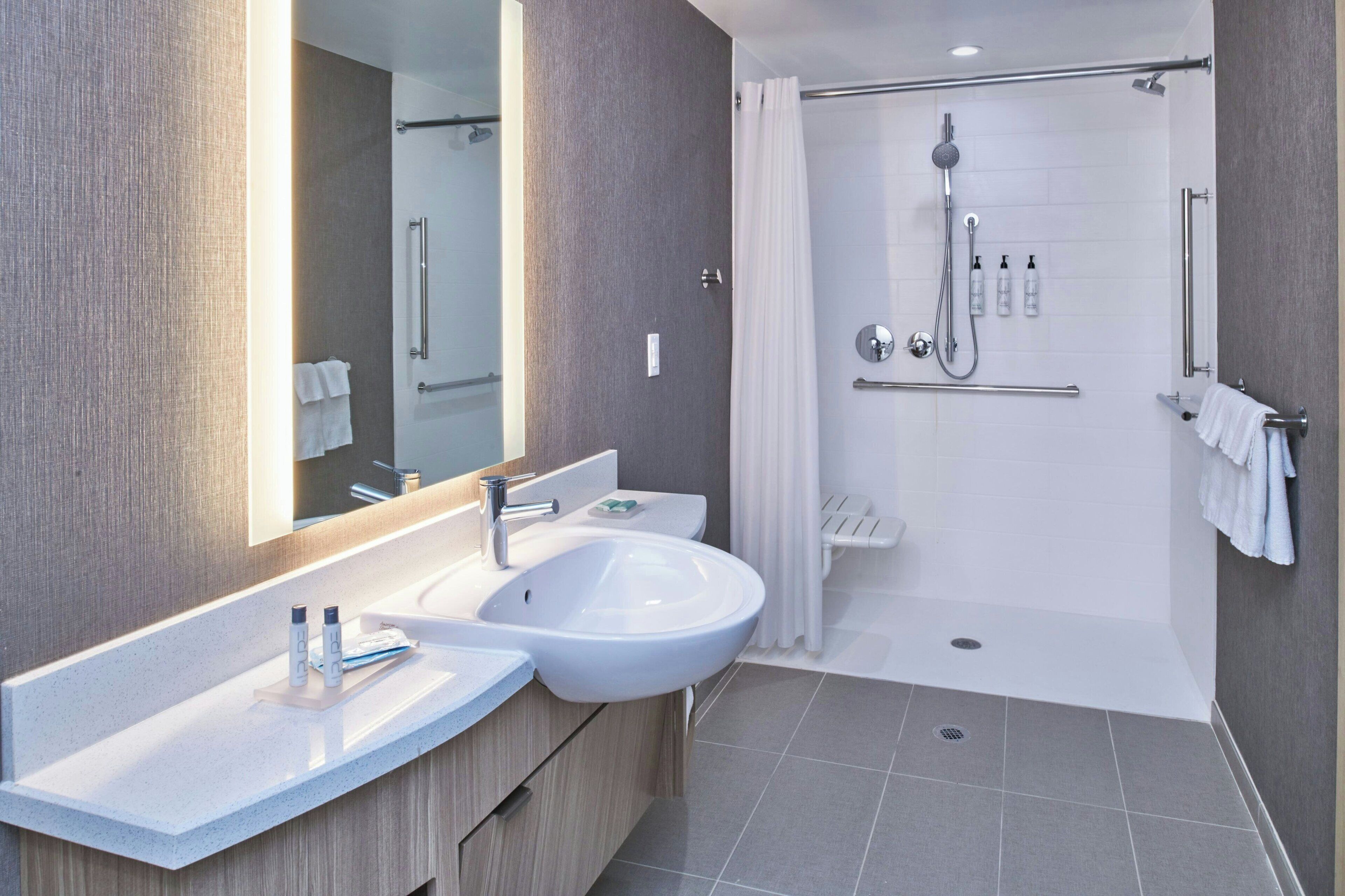 A modern bathroom with a double sink, a large mirror, a shower with a glass door, and a towel rack.