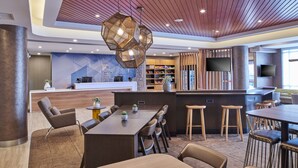 A modern hotel lobby with a reception desk, seating area, and bar. - SpringHill Suites by Marriott Detroit Dearborn (Dearborn)