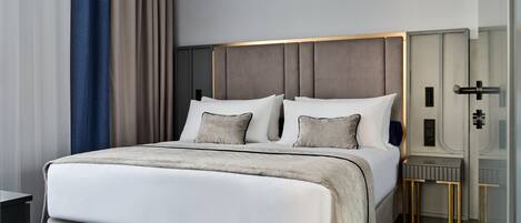 A modern bedroom with a large bed, a bedside table, and a nightstand.