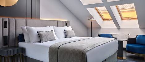 Quarto moderno com uma cama grande, uma escrivaninha e uma cadeira. Há claraboias no teto.