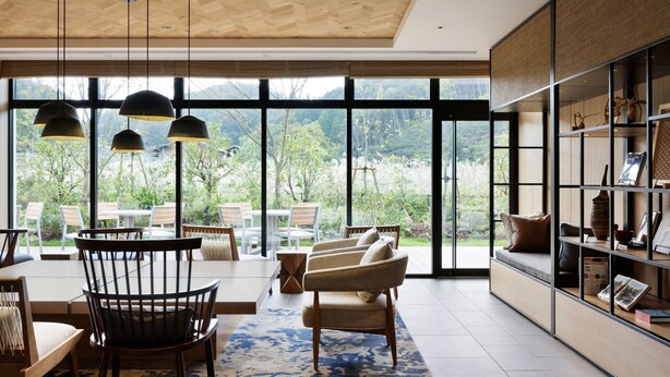 A modern living room with a large window, wooden ceiling, and a bookshelf. - Fairfield by Marriott Okayama Hiruzen Highland (Maniwa)