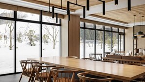 A spacious dining area with a long wooden table and chairs, large windows offering a view of a snowy landscape, and modern pendant lighting. - Fairfield by Marriott Okayama Hiruzen Highland (Maniwa)