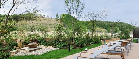 Una terraza con mobiliario exterior y un jardín con rocas y follaje.