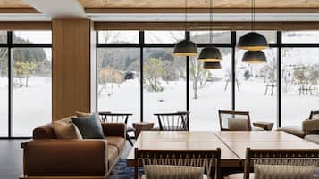 Un interior moderno con un ventanal grande, techo de madera y un comedor con mesa y sillas.