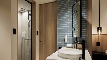 A modern bathroom with a glass shower, a white sink, and a mirror with a blue-tiled wall.