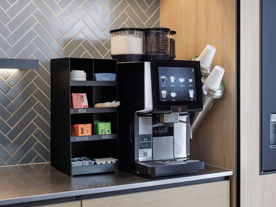 Una máquina de café con pantalla digital, un molinillo de café y un depósito para granos de café.