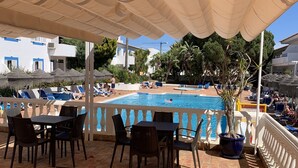 A poolside area with lounge chairs, a table, and a potted plant. - Best location in Lagos with superb pool area! (Lagos)
